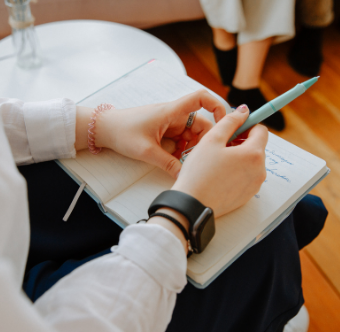 female hands with notepad on lap and blue pen